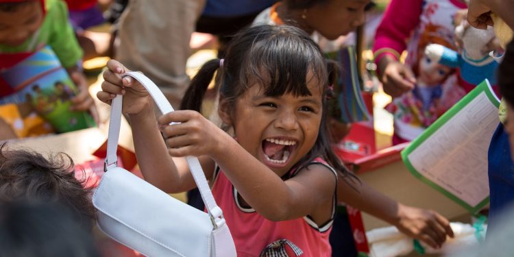 At a morning outreach event in a village in Cambodia, a girl rejoices at the purse she found inside her shoebox gift. (Photo is courtesy of Samaritan’s Purse)