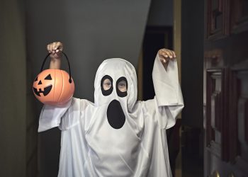 They knock on the door and when it opens, a boy dressed as a ghost appears in the foreground.  Trick or Treat!