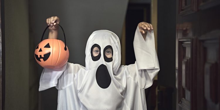 They knock on the door and when it opens, a boy dressed as a ghost appears in the foreground.  Trick or Treat!