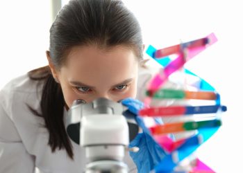 A woman biologist looks through a microscope close-up. DNA sample. Genetics research. Pharmaceutical laboratory