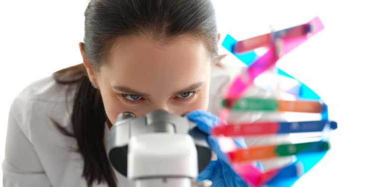 A woman biologist looks through a microscope close-up. DNA sample. Genetics research. Pharmaceutical laboratory