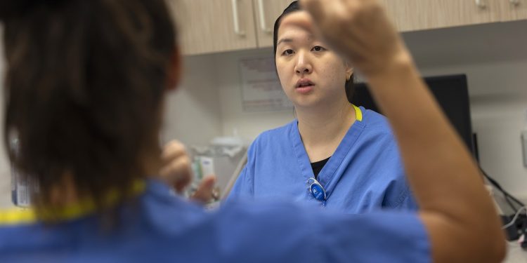 Interpreter Kendra Barlet signs to Edith Dong, a Deaf extern in audiology at Penn State Health Milton S. Hershey Medical Center, as Dong participates in a sedated auditory brainstem response evaluation to estimate hearing sensitivity on a patient.