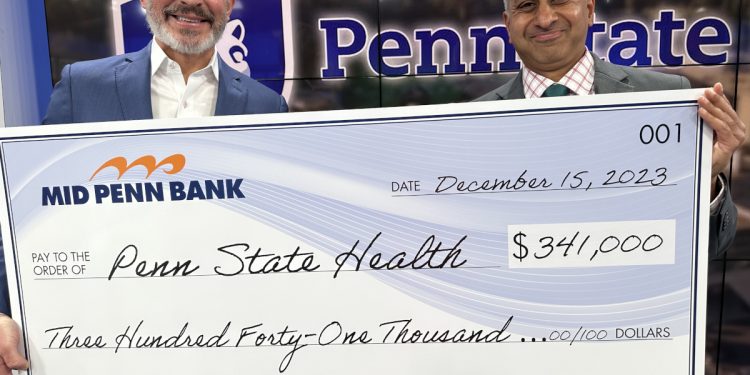  Rory Ritrievi, president and CEO of Mid Penn Bank (at left), and Dr. Jay Raman, interim chair of the Department of Urology at the Milton S. Hershey Medical Center, pose with an oversized check representing the amount raised in their 2023 "No Shave November" effort.