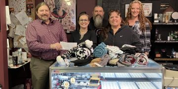 Left to right, MRAAA Director of Communications Steve Harmic accepts a cash donation, plus multiple donated items of hats, gloves, blankets, and more from New Image Tattoo Owner Christina Shaffer, and staff members Ed McGonigal, Chris Harris, and Jess Hoyt. All funds and items will benefit local senior citizens in need.
