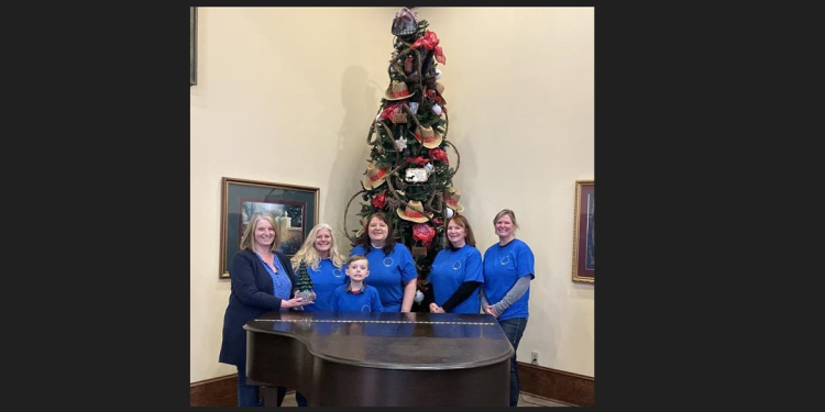 Kristen Zurat of the Chemo Care Bag Project, at left, hands off the Festival of the Trees traveling trophy to the latest winners, staff and volunteers with Full Circle Ranch Equine Haven. They are, left to right, Nancy Taylor, Sean McKeegan, Marty Butler, Suzanne Mosch, and Geremy Kephart.