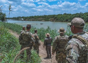 Soldiers from the Texas National Guard watch a Border Patrol helicopter hover above a group of civilians wading in the Rio Grande River along the Texas-Mexico border, May 22, 2023. The Soldiers patrol the southern border in support of Operation Lone Star to detect, deter, and interdict illegal immigrants before they enter Texas communities.

Pvt. Steven Day | Texas National Guard