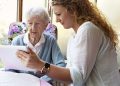 young caregiver showing something to senior woman, 90 years old, on digital tablet