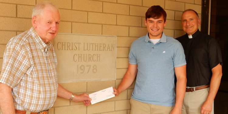 James Dunlap (left) presents the Sandra Dunlap Scholarship to Carson Dombroski. The Rev. John Miller, pastor Christ Lutheran Church, is at right.