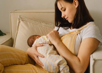 Newborn baby boy sucking milk from mothers breast. Portrait of mom and breastfeeding baby. Concept of healthy and natural baby breastfeeding nutrition.