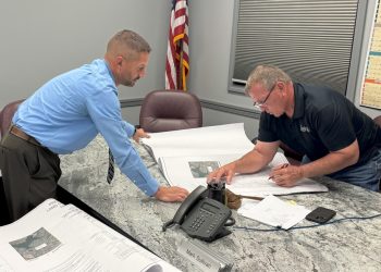 Township/City Manager Shawn Arbaugh holds down land development plans for Supervisor Mark Sullivan to sign. (Photo by Steven McDole)