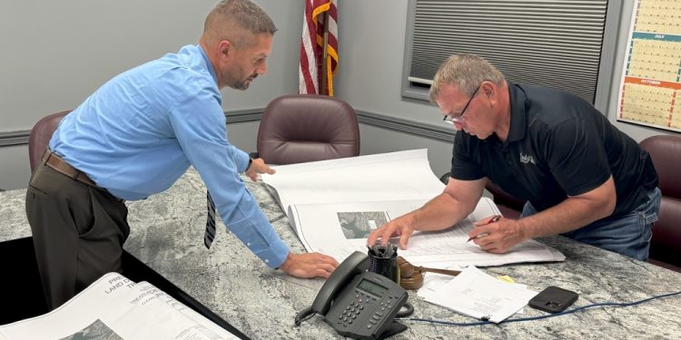 Township/City Manager Shawn Arbaugh holds down land development plans for Supervisor Mark Sullivan to sign. (Photo by Steven McDole)