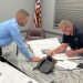 Township/City Manager Shawn Arbaugh holds down land development plans for Supervisor Mark Sullivan to sign. (Photo by Steven McDole)