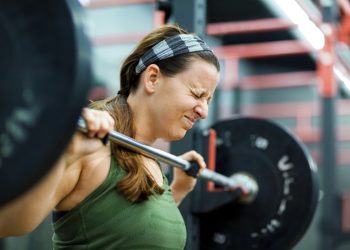 Young woman lifting weights in gym