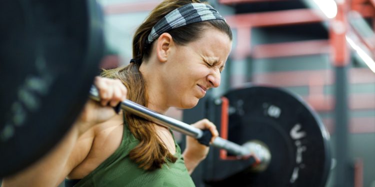 Young woman lifting weights in gym