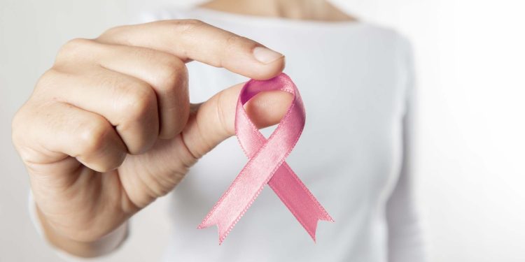 Hands holding pink awareness ribbon.