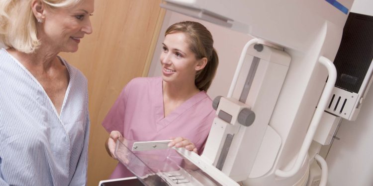 Nurse Assisting Older Patient About To Have A Mammogram In Hospital Room