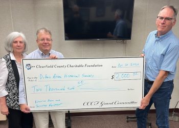 The DuBois Area Historical Society recently accepted a $2,000 grant from the Clearfield County Charitable Foundation. Pictured, from left, are: Kathleen Clement, president of Historical Society Board; Mark Gimcrackery, executive director of the Charitable Foundation; and Tom Rubritz, board member/buildings and grounds for the Historical Society.   In the background is the new TV purchased with grant funds.