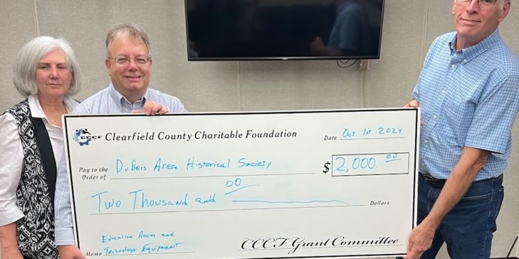 The DuBois Area Historical Society recently accepted a $2,000 grant from the Clearfield County Charitable Foundation. Pictured, from left, are: Kathleen Clement, president of Historical Society Board; Mark Gimcrackery, executive director of the Charitable Foundation; and Tom Rubritz, board member/buildings and grounds for the Historical Society.   In the background is the new TV purchased with grant funds.