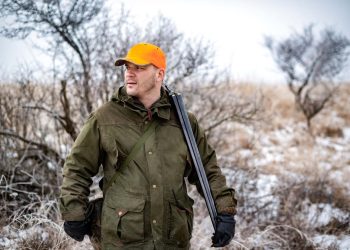 Hunter in the forest holding a rifle and stalking his prey.